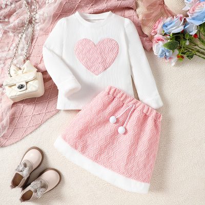 Pink and white girl’s sweater and skirt set, perfect for casual or dressy occasions, featuring heart and geometric patterns with cozy fabric, ideal for children's fashion.