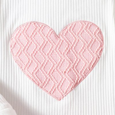 Pink heart-shaped plush rug with textured geometric pattern, perfect for home decor and cozy accents. Ideal for adding warmth to living spaces or bedrooms.
