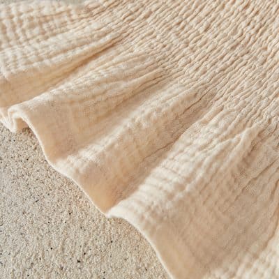Soft beige textured fabric with a crinkled pattern, ideal for beach towels or casual summer accessories from Monalisa Store. Perfect for stylish, comfortable, and absorbent textiles.
