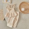 Soft beige baby clothing set with ruffled top and comfortable pants, styled with wicker decor, perfect for cozy and stylish infants.