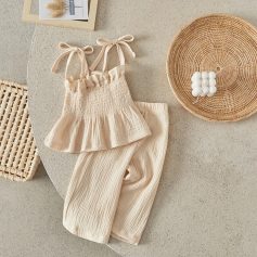 Soft beige baby clothing set with ruffled top and comfortable pants, styled with wicker decor, perfect for cozy and stylish infants.