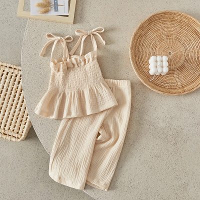 Soft beige baby clothing set with ruffled top and comfortable pants, styled with wicker decor, perfect for cozy and stylish infants.