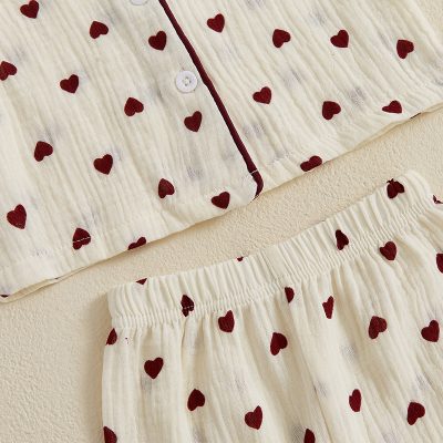 Soft ivory pajama set with red heart patterns, featuring a button-up shirt and elastic waistband shorts, perfect for comfortable sleepwear or loungewear.