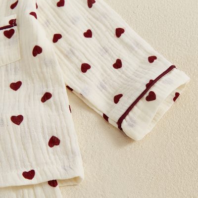 Ultra-soft white medical gown with red heart patterns, ideal for patient comfort and healthcare settings, featuring a secure wrist cuff for easy wear and removal.