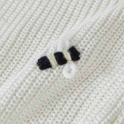 Soft white knitted fabric with cute bee embroidery, perfect for baby clothes or cozy accessories.