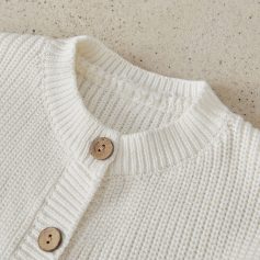 Soft white knitted cardigan with wooden buttons, perfect for stylish winter fashion and cozy comfort.