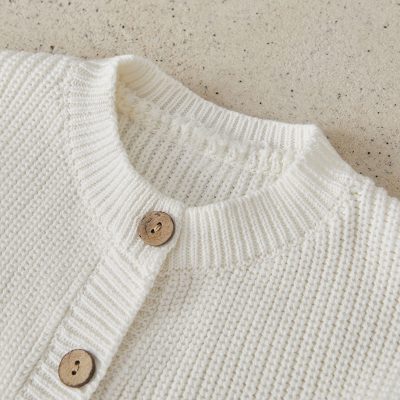 Soft white knitted cardigan with wooden buttons, perfect for stylish winter fashion and cozy comfort.
