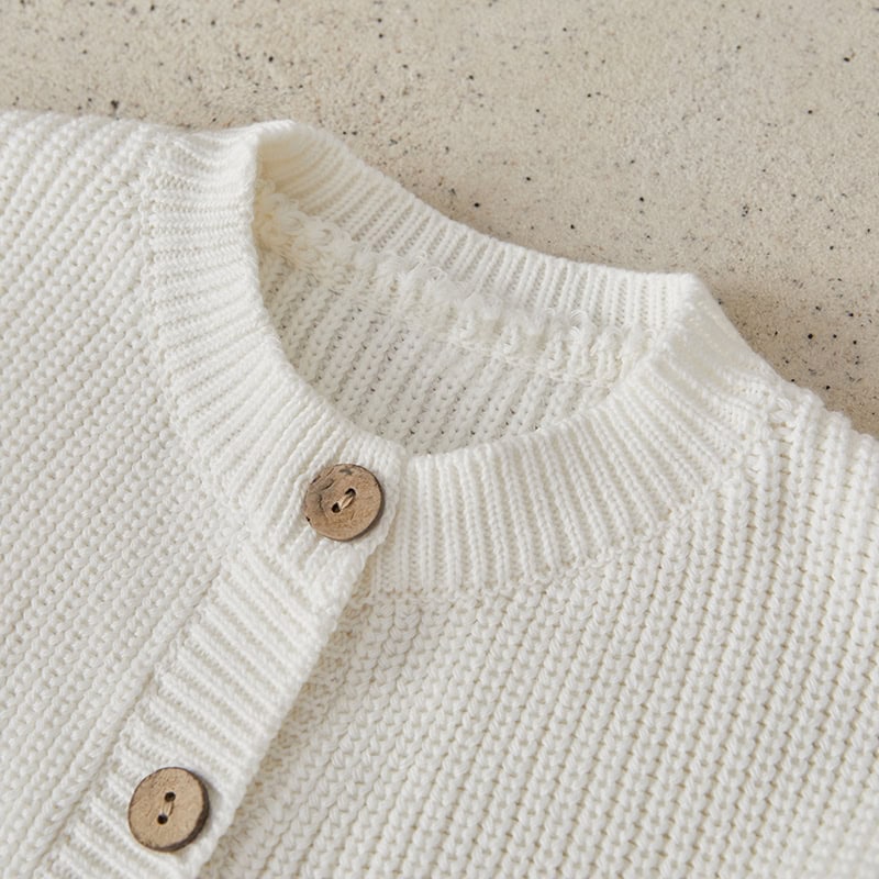 Soft white knitted cardigan with wooden buttons, perfect for stylish winter fashion and cozy comfort.
