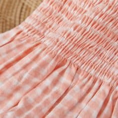 Pink checkered fabric with gathered elastic waistband for comfortable women's clothing.