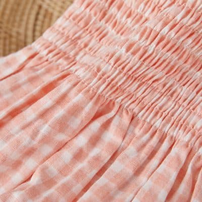 Pink checkered fabric with gathered elastic waistband for comfortable women's clothing.