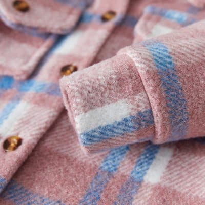 Soft pink plaid flannel shirt with blue and white accents, featuring brown buttons, perfect for cozy winter wear.