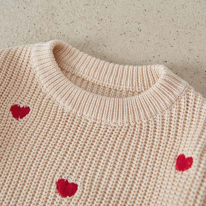 Soft beige knit sweater with red heart embroidery, cozy and stylish for Valentine’s Day or casual wear, featuring high-quality craftsmanship and a comfortable fit.