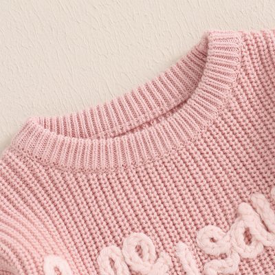 Pink knitted sweater with embossed text, cozy fashion garment, soft wool material, casual style, women's winter wear, Monalisa Store fashionable clothing, premium knitwear, stylish and comfortable, gift ideas for cold weather, trendy knit sweater for women.