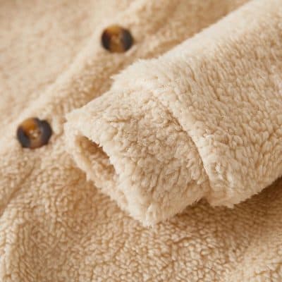 Soft beige fleece fabric with brown buttons, perfect for cozy warm clothing and accessories. Ideal for winter wear, offering comfort and style.