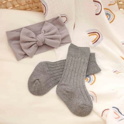 Soft grey ribbed socks and a matching headband set on a cozy bed with rainbow patterned bedding, perfect for comfortable fashion accessories from Monalisa Store.