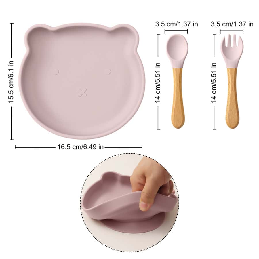 Soft pink bear-shaped silicone plate with removable divided sections, perfect for kids’ meals, and matching wooden spoon and fork, ideal for pediatric dentistry and child-friendly dining.