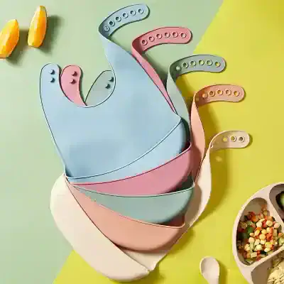 Silicone bibs in pastel colors for baby feeding, designed with adjustable neck straps for a comfortable fit, ideal for preventing messes during meals.