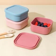 Silicone food storage containers in pastel pink and blue, ideal for healthy meal prep and storage, featuring lids and a bowl with fresh berries, perfect for modern kitchen organization.