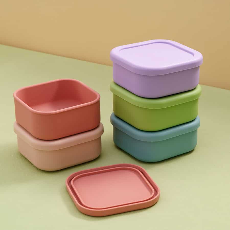 Colorful silicone storage containers in pastel shades stacked on a pastel background, ideal for food storage and organization.