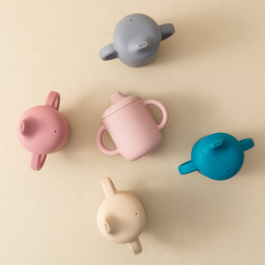 Colorful baby bottles shaped like animals, pink, blue, gray, white, and peach, on a cream background, cute baby feeding accessories, modern infant feeding supplies, Monalisa Store baby products, safe and stylish bottles for babies.