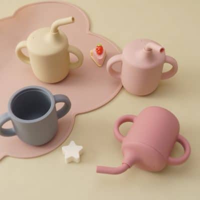 Colorful silicone water bottles and mini toy-sized teapots for kids, perfect for playful hydration accessories, on a pastel pink tray for children’s drinkware and toy collection, Monalisa Store.