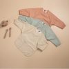 Soft pastel-colored oversized sweatshirts in peach, mint green, and cream, perfect for casual or loungewear, displayed on a neutral background with minimalist accessories.