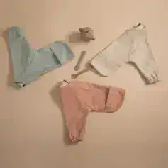 Soft pastel-colored disposable underwear for women, laid out on a neutral background with small skincare and beauty tools nearby. Comfortable, lightweight, perfect for medical or personal care use.