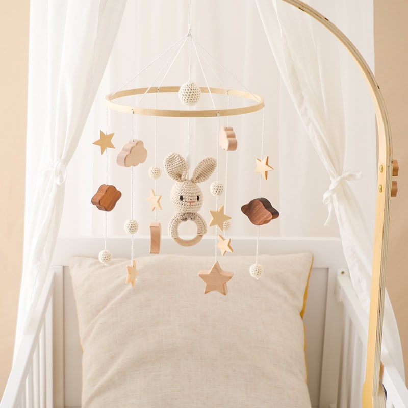 Soft baby crib with cozy pillow and plush bunny mobile for infant nursery decor, ideal for gentle sleep and sensory development. Perfect for ensuring a calming bedtime environment for babies.