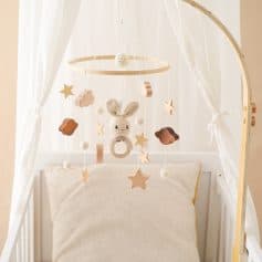 Soft baby cradle with plush bunny mobile, clouds, stars, and wooden hanging toys, perfect for nursery decor and infant comfort.