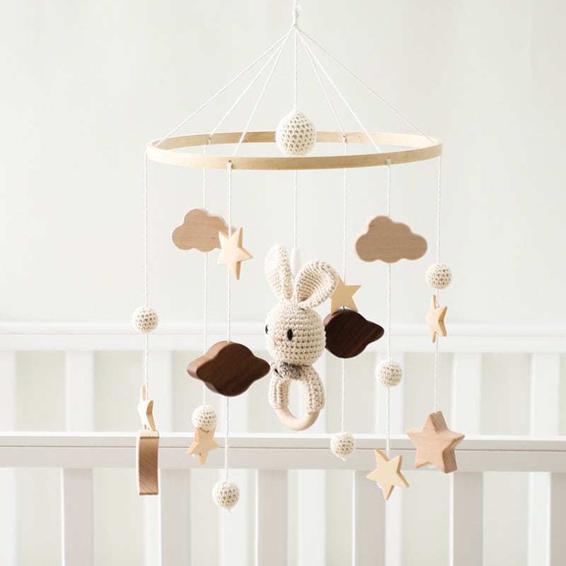 Soft neutral-toned baby mobile with plush bunny, wooden stars, and cloud shapes for nursery decoration and infant visual stimulation. Perfect for a cozy, calming nursery setting.