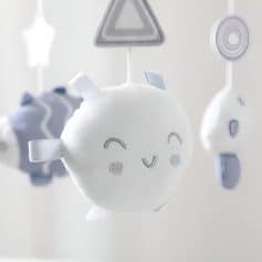 White plush baby mobile with smiling face and hanging geometric shapes, perfect for infant eye development and nursery decoration.