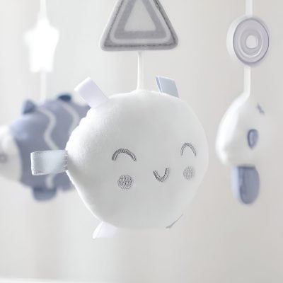 White plush baby mobile with smiling face and hanging geometric shapes, perfect for infant eye development and nursery decoration.