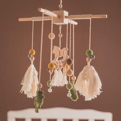 Handmade baby crib mobile with wooden and felt elements, soft tassels, and playful animal figures for nursery decor.
