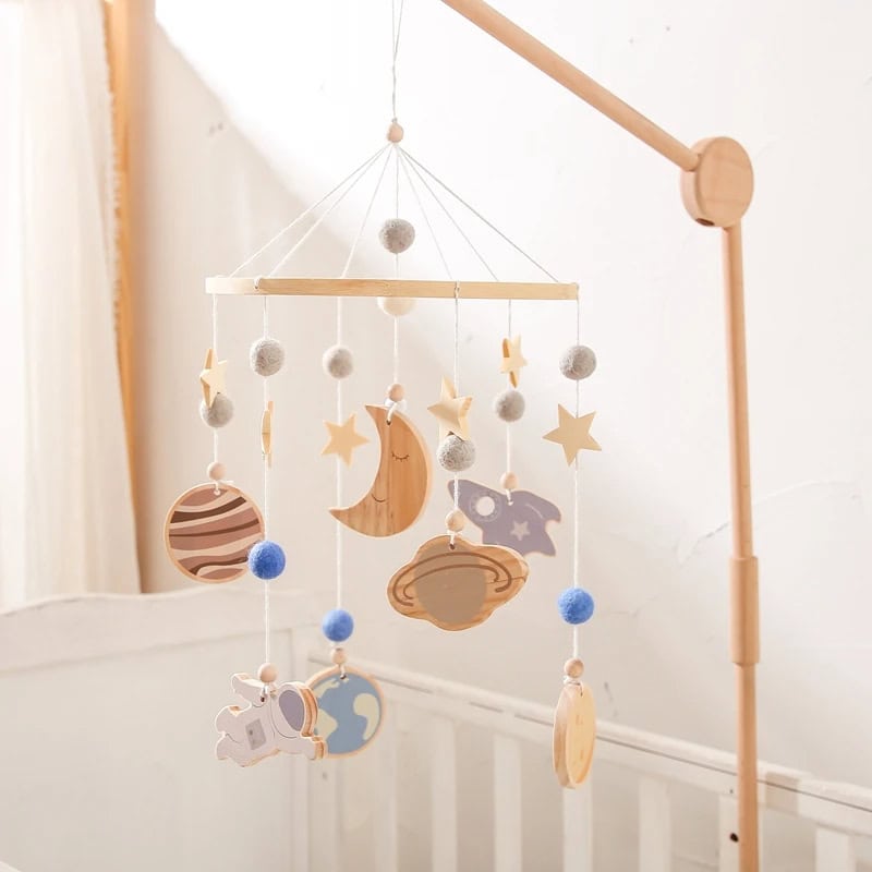 Wooden baby mobile with stars, moon, planets, and astronaut ornaments for nursery decor, crafted from natural wood and felt, creating a calming celestial theme for infants and toddlers.