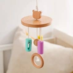 Colorful wooden baby crib mobile with hanging toys, soft natural wood, pastel-colored cylinders, and rings, ideal for stimulating infants and enhancing nursery decor.