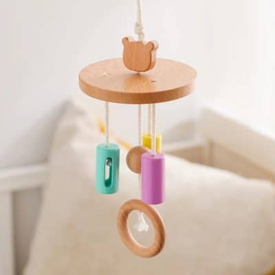 Colorful wooden baby crib mobile with hanging toys, soft natural wood, pastel-colored cylinders, and rings, ideal for stimulating infants and enhancing nursery decor.