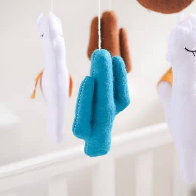 Soft plush baby hand puppet toy hanging on a string with other puppet toys in the background, used for child entertainment and sensory play.