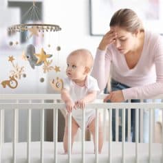 Sleeping baby girl with mother, nursery scene with hanging mobile, cozy baby room decor, infant care at Monalisa Medical store, safe and comfortable baby environment.