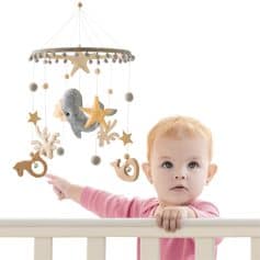 Wooden baby crib mobile with plush whale and star decorations for nursery decor.