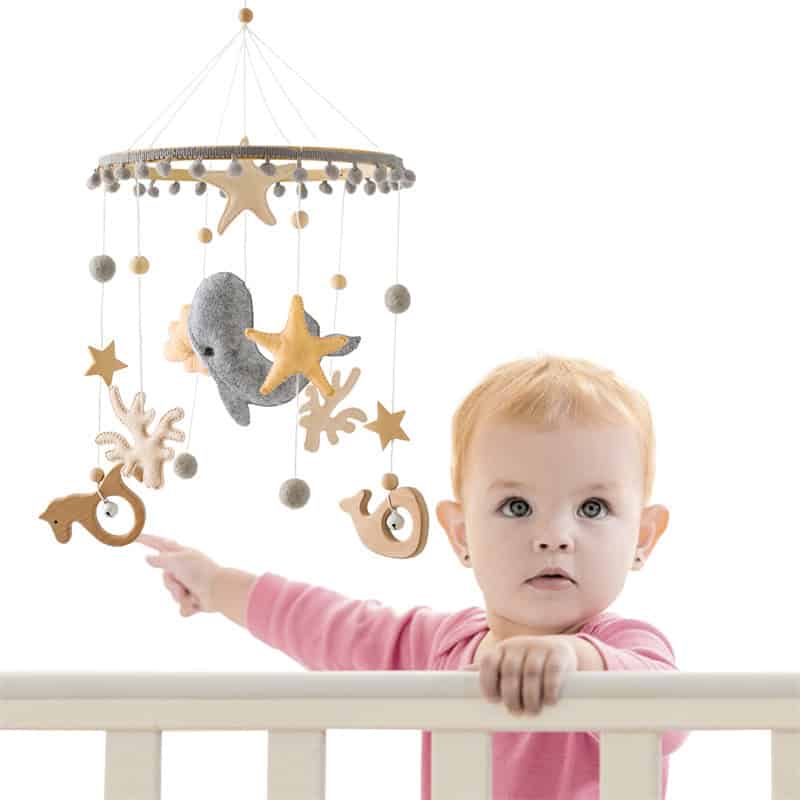 Wooden baby crib mobile with plush whale and star decorations for nursery decor.