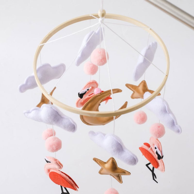 Delicate pink flamingo and star-themed baby mobile with plush clouds and pom-poms, perfect for a nursery or baby room decor, promoting a calming and whimsical environment.