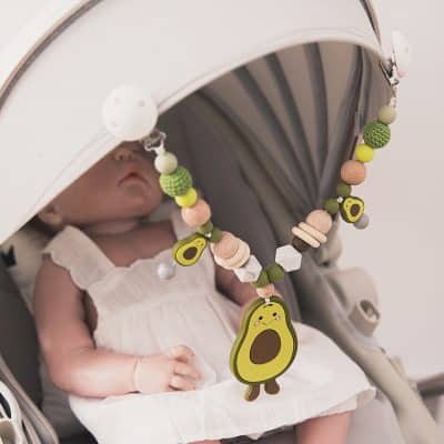 Colorful baby stroller teething toy with avocado design, made of silicone and wood, perfect for teething babies and developmental play.