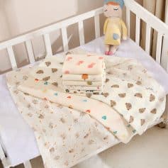 Soft baby blankets with adorable animal and heart patterns on a white crib bed, ideal for nursery bedding and cozy sleep for infants, from Monalisa Medical store.