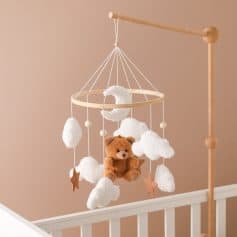 Soft plush teddy bear on a dreamy cloud-themed baby mobile for nursery decor and infant sleep comfort.