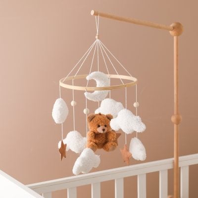 Soft plush teddy bear on a dreamy cloud-themed baby mobile for nursery decor and infant sleep comfort.