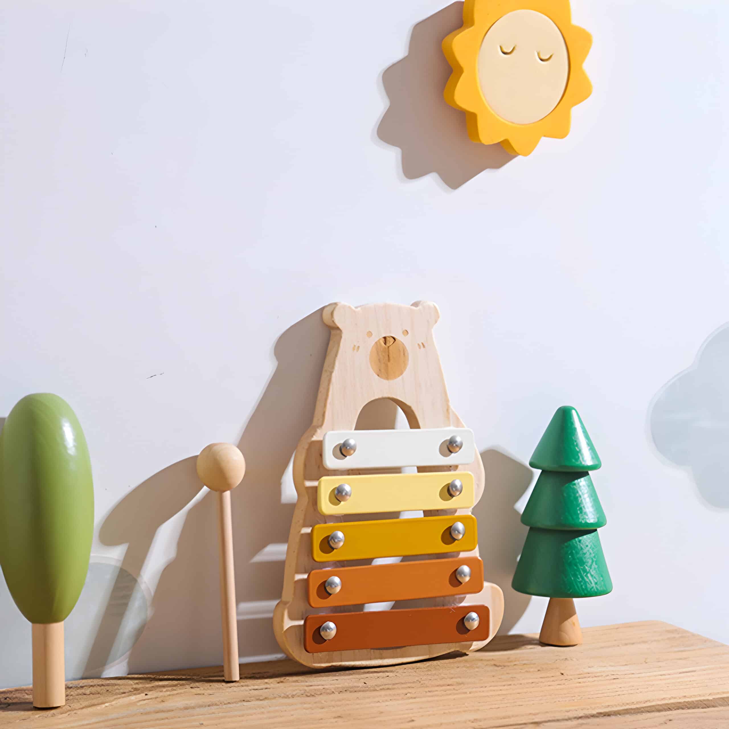 Bright wooden toy xylophone with colorful bars, set against a playful children's room decor featuring trees and sun wall art, ideal for kids' sensory and musical development.