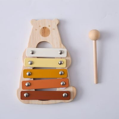 Colorful wooden bear-shaped xylophone with metal bars in yellow, orange, and brown, accompanied by a wooden mallet, designed for children's musical development, play, and early learning.