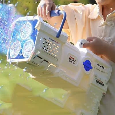 Blowing soap bubbles outdoors with bubble gun toy, child playing during sunny day, colorful bubbles floating in air, fun activity for kids, summer recreational toy for children, Monalisa Store promotional image for kids' toys and outdoor entertainment options.
