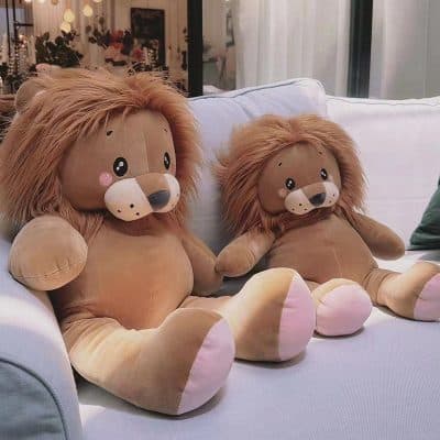 Lion plush toys sitting on a white couch with decorative pillows, ideal for children's toys and home decor, showcasing soft, cuddly material and adorable design.