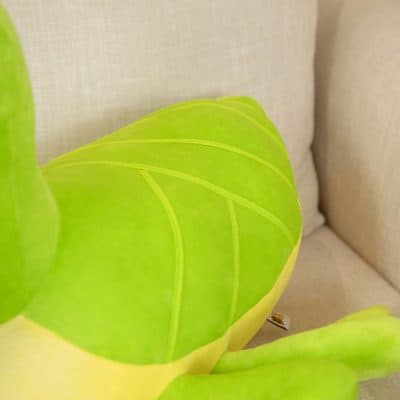 Bright green tropical plant leaf with prominent yellow veins, close-up detail, placed on a beige fabric sofa background, showcasing vibrant natural foliage.